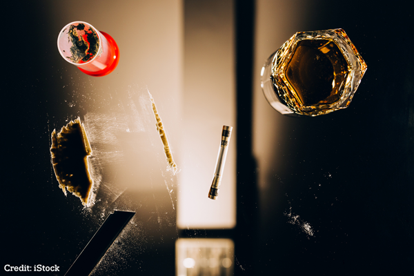View through a glass table with a glass of alcohol, powder and a syringe