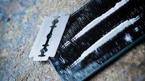 lines of cocaine on a mirror alongside a razor blade