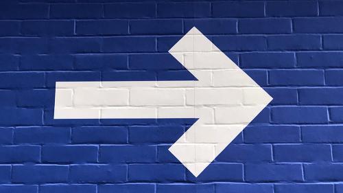 White arrow pointing to the right on blue brick wall