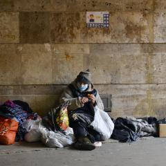 homeless woman in medical mask sits in an underground passage