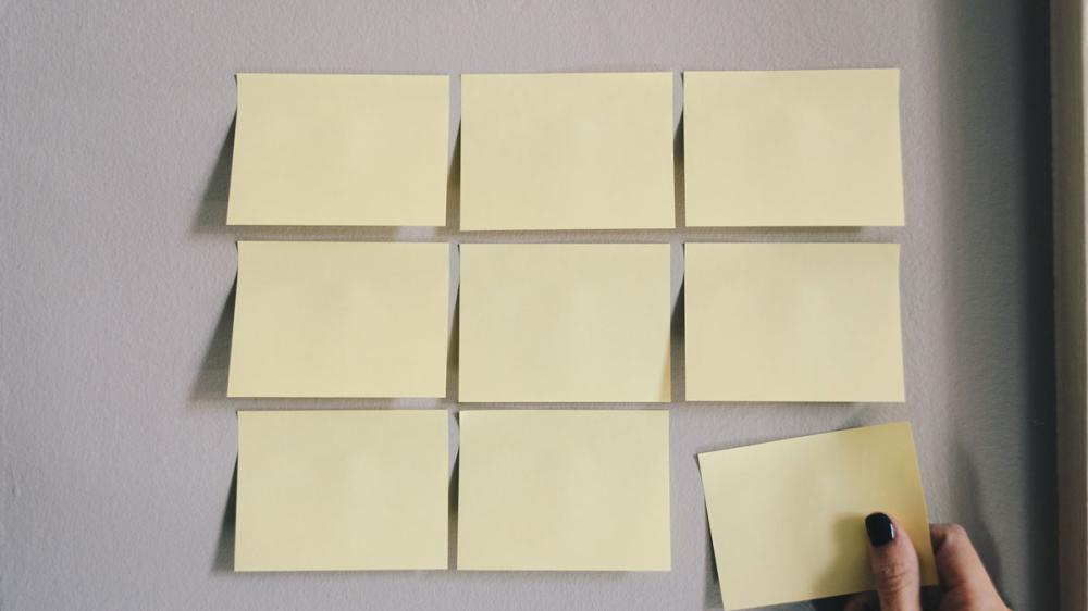 Nine blank yellow post-its on a wall